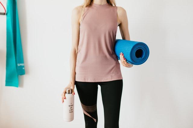 woman carrying blue fitness mat and water bottle